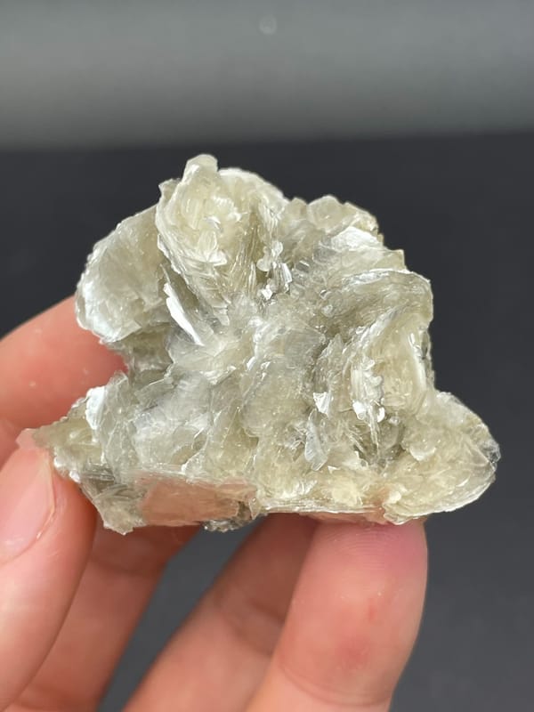Silvery mica book cluster from Xuebaoding, Sichuan, China, held in hand
