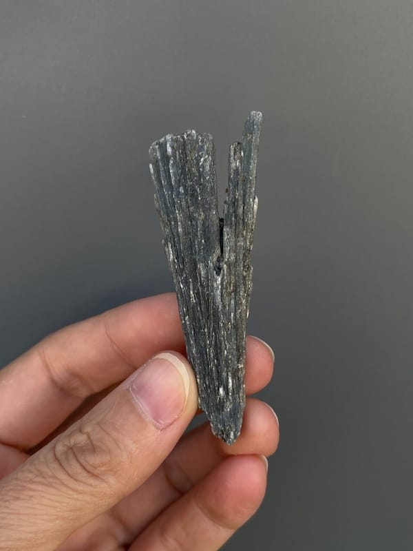 Steel blue-grey bladed kyanite crystal from Madagascar, held in hand