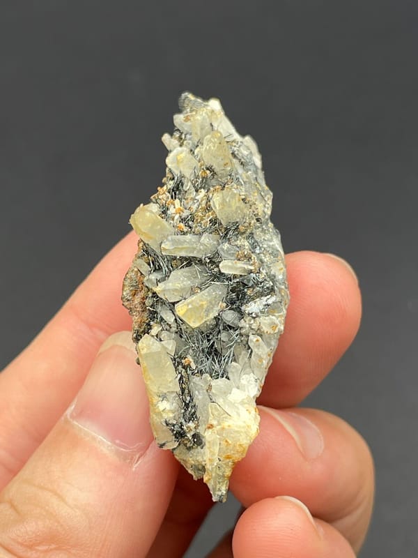 Dark metallic bismuthinite with pale quartz crystals, Inner Mongolia, China, close-up of the crystal faces