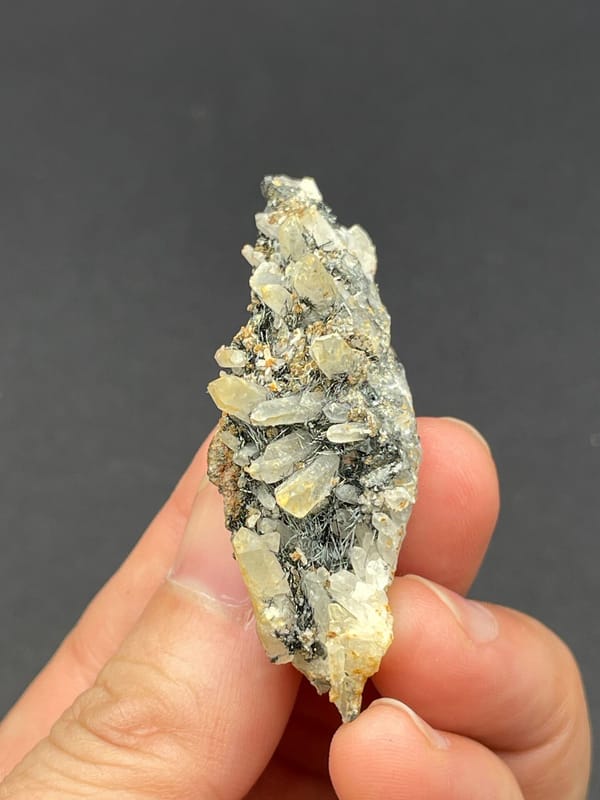 Dark metallic bismuthinite with pale quartz crystals, Inner Mongolia, China, detail of the matrix contact