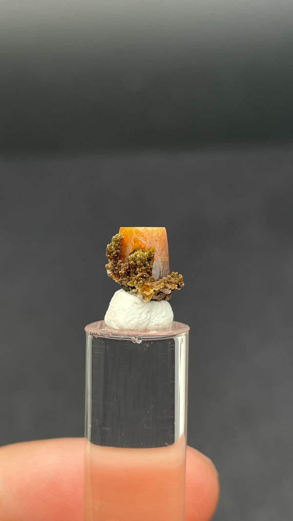 Small orange tabular wulfenite crystal on matrix from Mexico, shown on a stand
