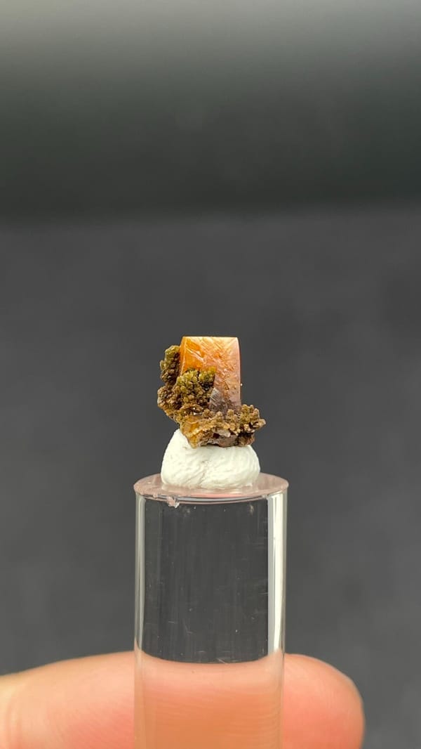 Small orange tabular wulfenite crystal on matrix from Mexico, shown on a stand, second angle
