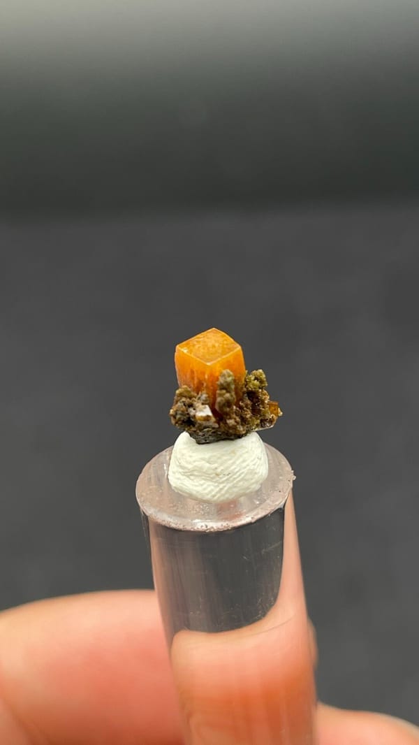 Small orange tabular wulfenite crystal on matrix from Mexico, shown on a stand, top view