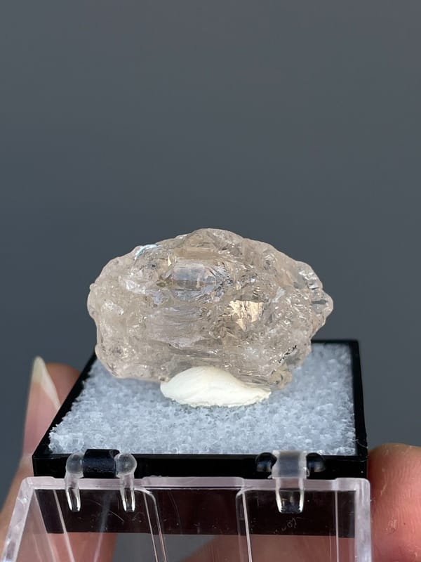 Pale straw topaz crystal in white matrix from Yunnan, China, in a display box, detail of the matrix contact