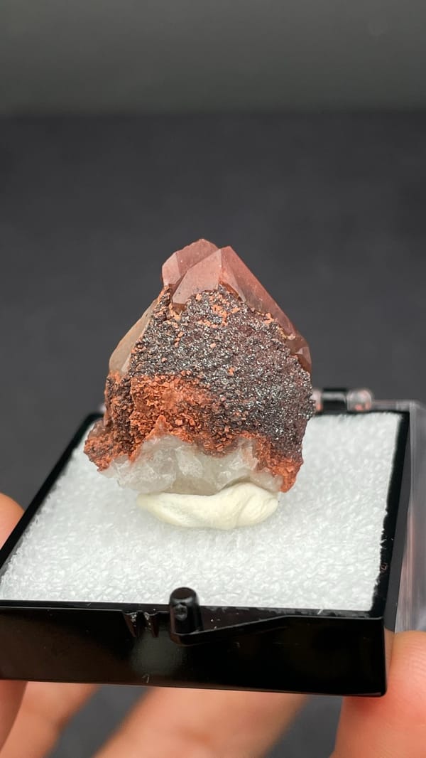 Pink-red quartz point with dark hematite crust from Shanxi, China, in a box