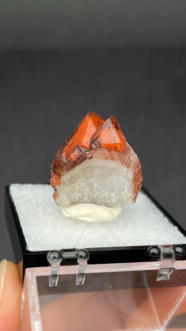 Pink-red quartz point with dark hematite crust from Shanxi, China, in a box, reverse side