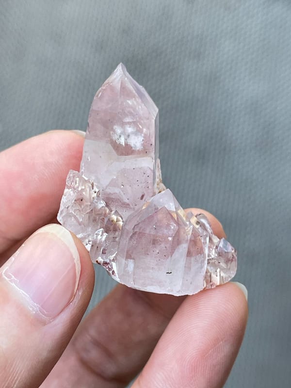 Rose-tinted quartz point group from India, held in hand