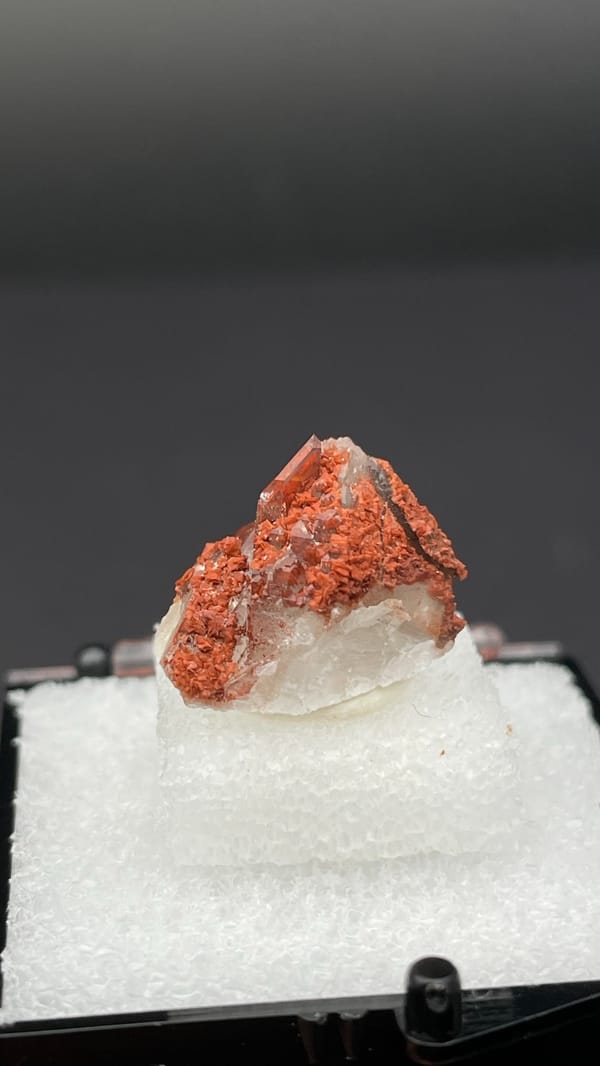 Small deep red hematoid quartz crystal group from Shanxi, China, in a display box, close-up of the crystal faces