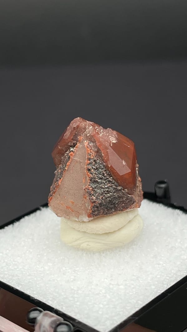 Orange-red hematoid quartz crystal with a clear amber tip from Shanxi, China, detail of the matrix contact