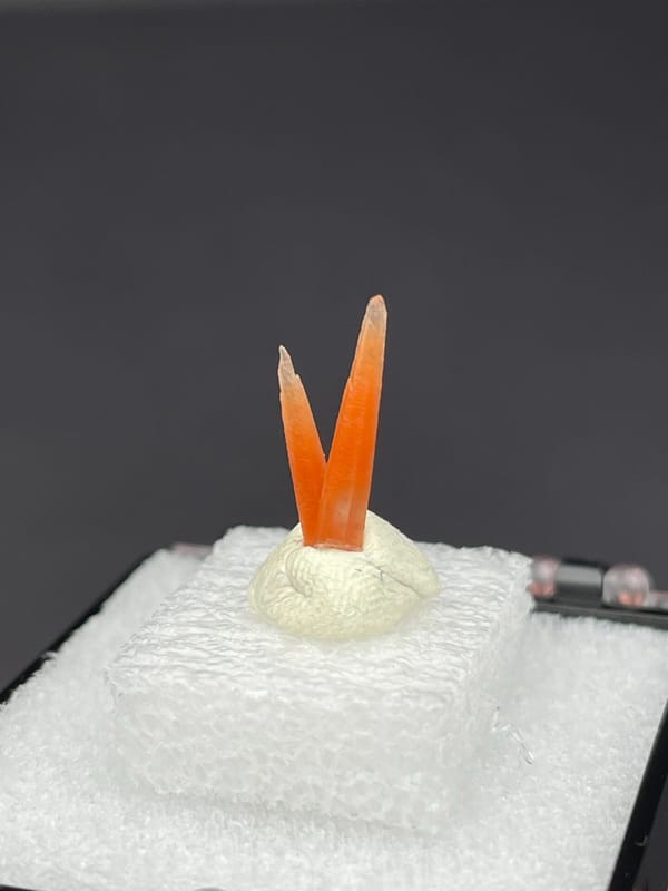 Two slim orange-red hematoid quartz points from Guangdong, China, on a mount, second angle