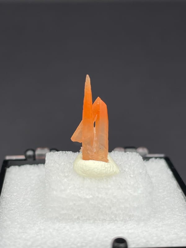 Slim orange-red hematoid quartz point from Guangdong, China, in a display box