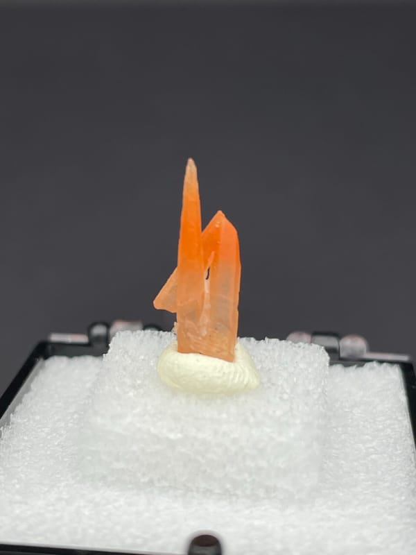 Slim orange-red hematoid quartz point from Guangdong, China, in a display box, second angle