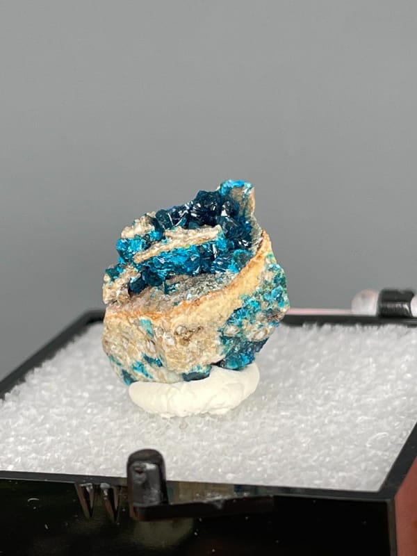 Blue veszelyite divided by a tan rock seam from Yunnan, China, in a box, reverse side