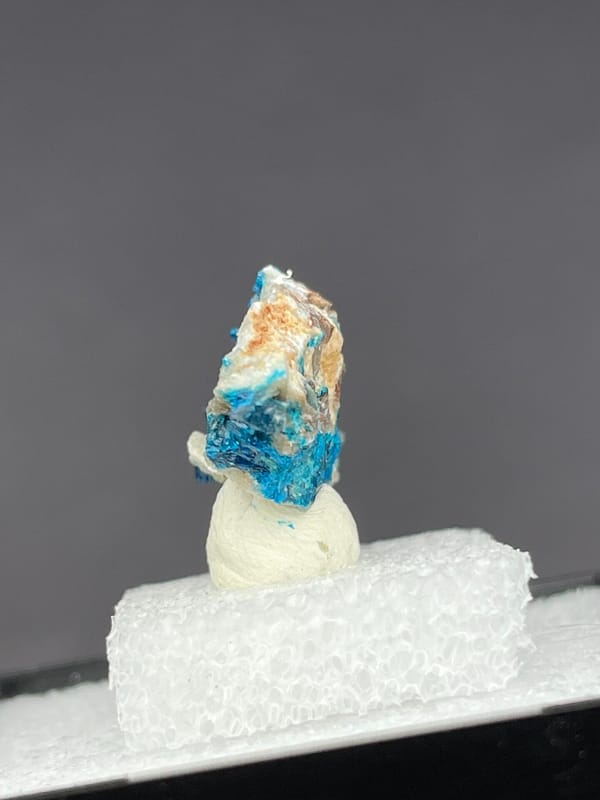 Vivid blue veszelyite on a pale green-white crust from Yunnan, China, in a box, close-up of the crystal faces