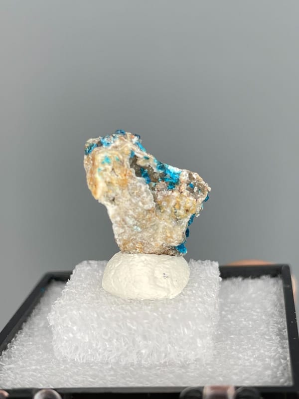 Blue veszelyite crust crossed by a pale vein, Yunnan, China, in a display box, detail of the matrix contact
