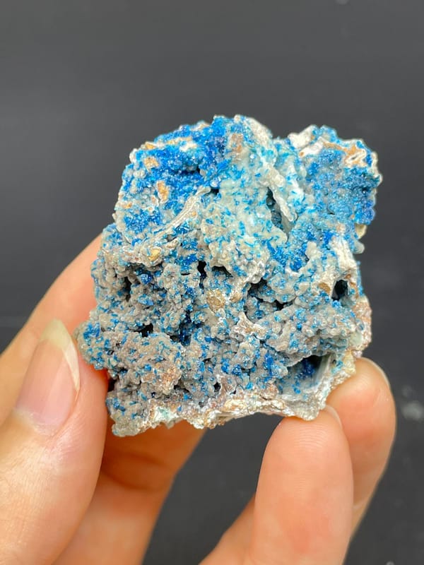 Strong blue veszelyite crust over pale rock from Yunnan, China, held in hand