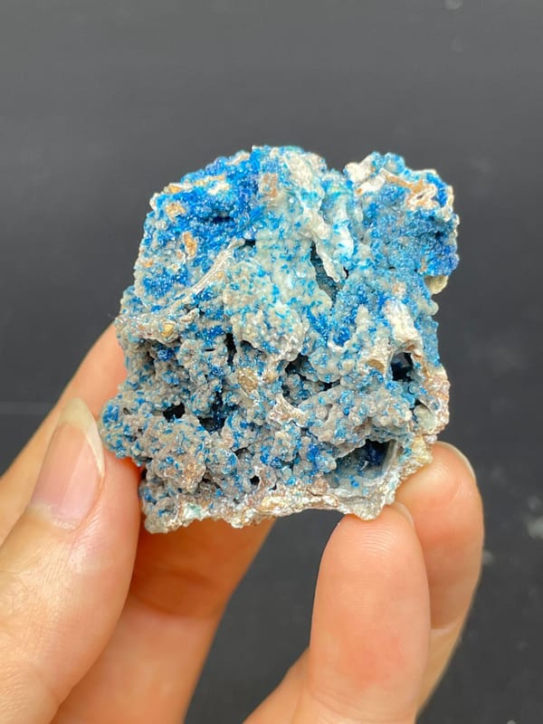 Strong blue veszelyite crust over pale rock from Yunnan, China, close-up of the crystal faces