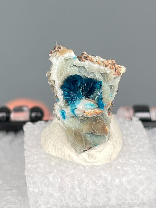 Small deep blue veszelyite crust on pale rock from Yunnan, China, in a box, top view