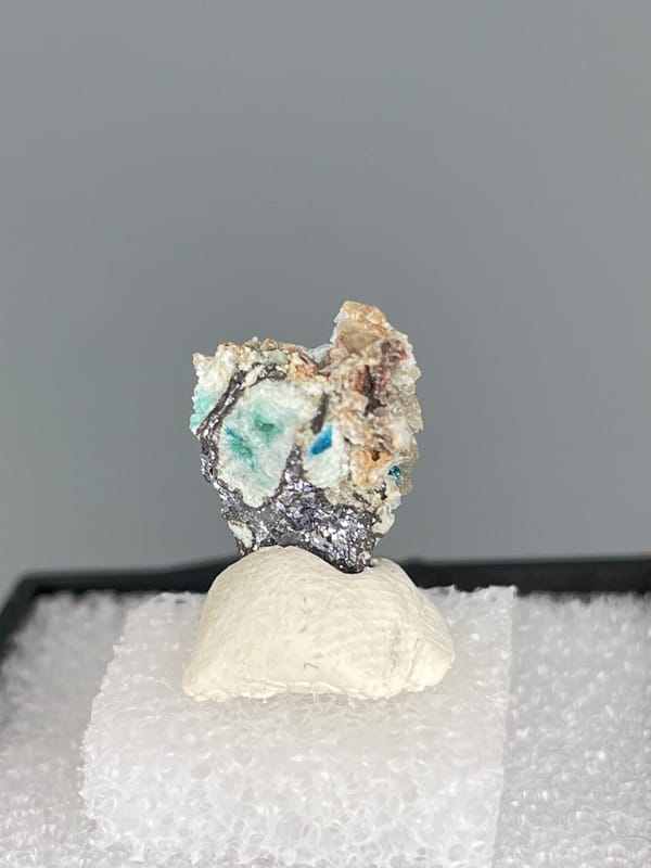 Small deep blue veszelyite crust on pale rock from Yunnan, China, in a box, detail of the matrix contact