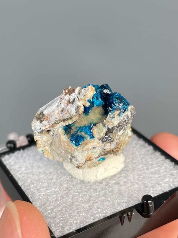 Deep blue veszelyite in the hollows of a pale cream rock, Yunnan, China, close-up of the crystal faces