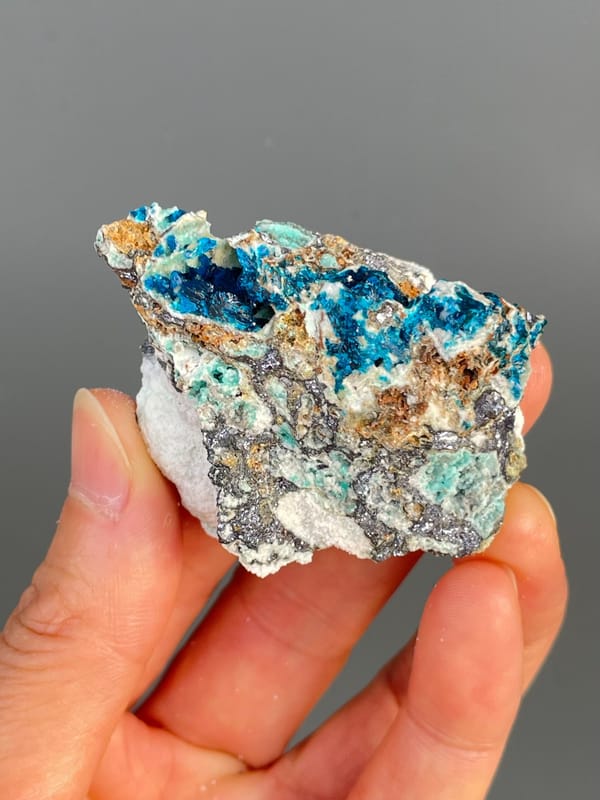 Deep blue veszelyite with turquoise patches on grey rock from Yunnan, China, close-up of the crystal faces