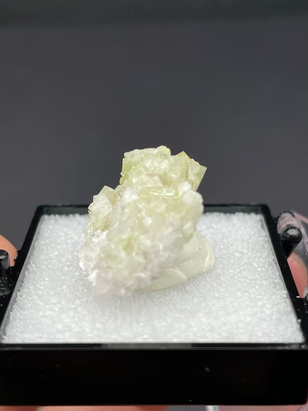 Pale green tourmaline crystal spray from Afghanistan, in a display box, close-up of the crystal faces