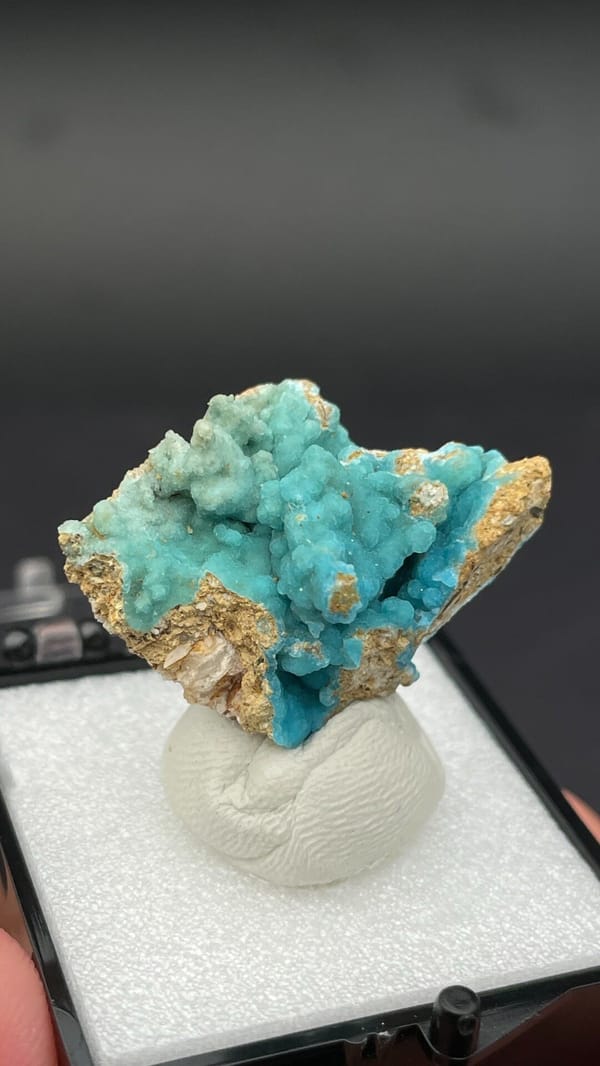 Turquoise botryoidal hemimorphite on tan matrix from Yunnan, China, in a box, close-up of the crystal faces
