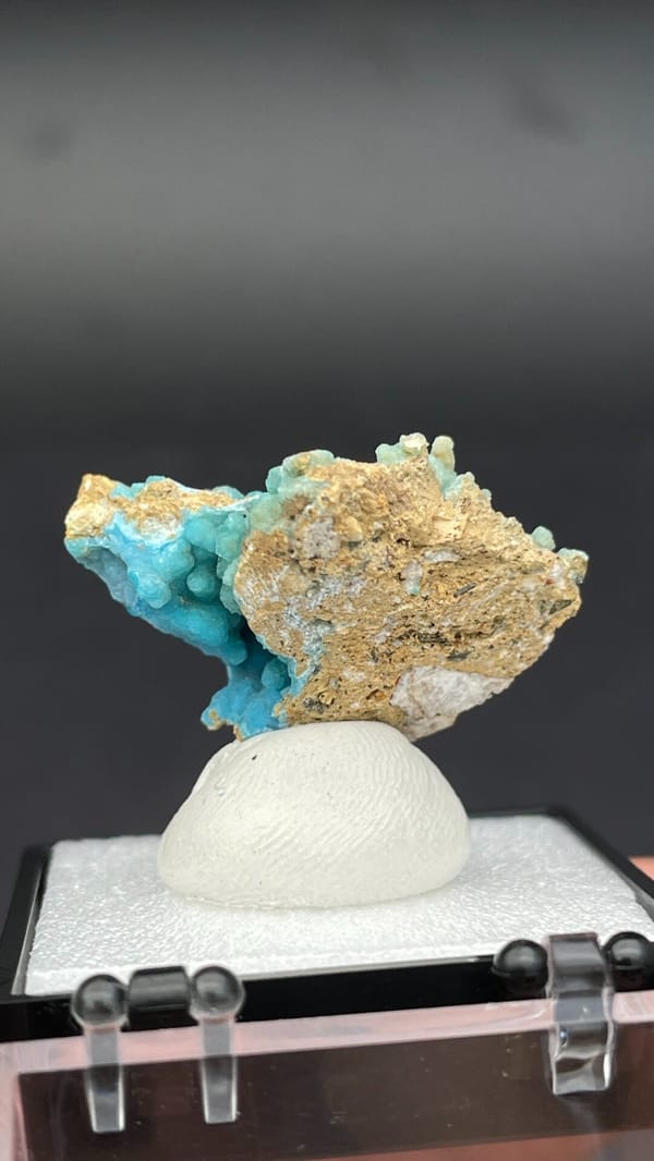 Turquoise botryoidal hemimorphite on tan matrix from Yunnan, China, in a box, detail of the matrix contact