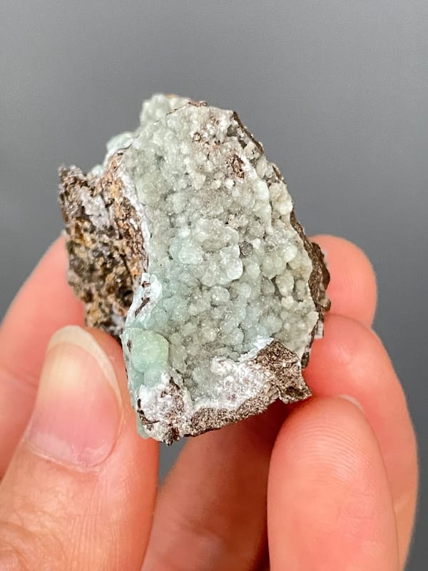 Pale mint-green hemimorphite lining a brown rock cavity from Yunnan, China, close-up of the crystal faces