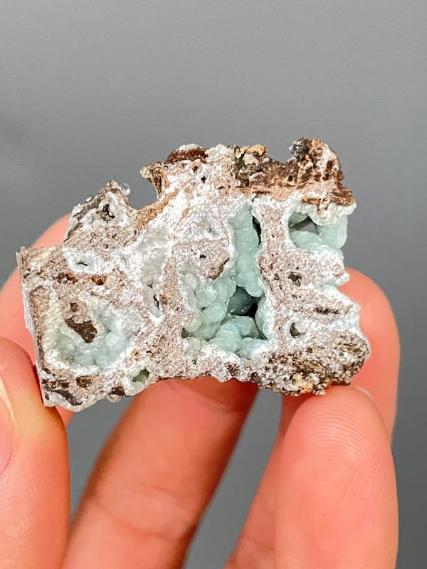 Pale mint-green hemimorphite lining a brown rock cavity from Yunnan, China, detail of the matrix contact