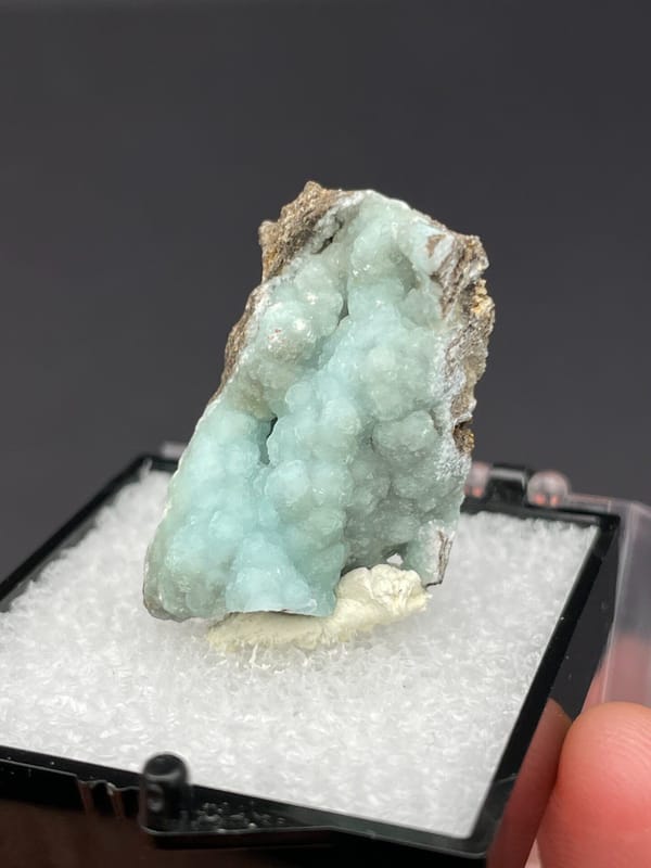 Pale mint hemimorphite crust on brown rock from Yunnan, China, in a box