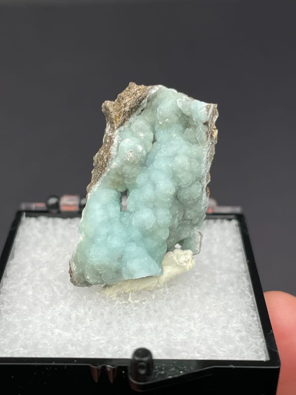 Pale mint hemimorphite crust on brown rock from Yunnan, China, in a box, second angle