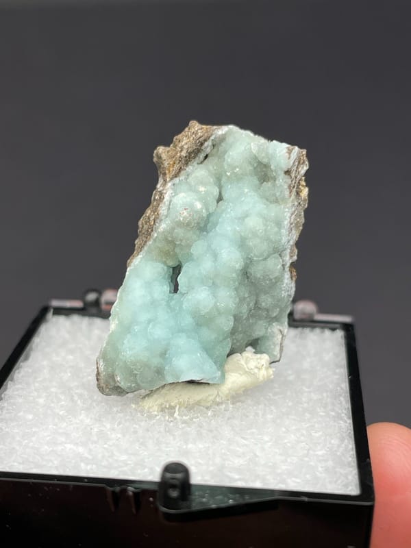Pale mint hemimorphite crust on brown rock from Yunnan, China, in a box, close-up of the crystal faces