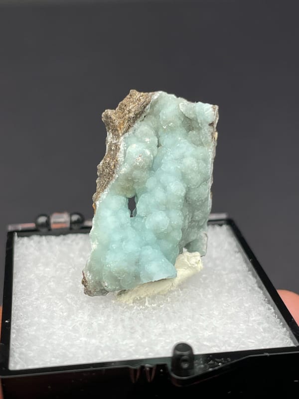 Pale mint hemimorphite crust on brown rock from Yunnan, China, in a box, top view