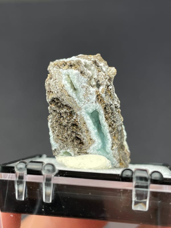 Pale mint hemimorphite crust on brown rock from Yunnan, China, in a box, detail of the matrix contact