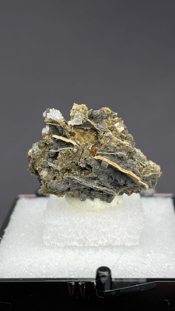 White bladed hemimorphite flowers on dark matrix from Guangxi, China, in a box, close-up of the crystal faces