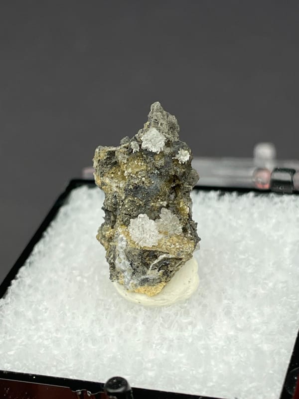 Colourless hemimorphite flower rosette on dark matrix from Guangxi, China, reverse side