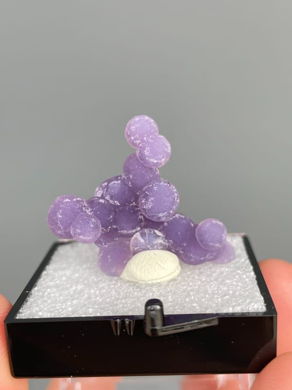 Cluster of purple botryoidal grape agate spheres from Indonesia, in a box