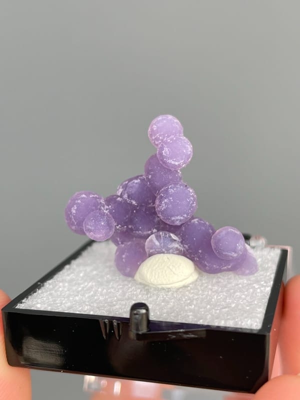 Cluster of purple botryoidal grape agate spheres from Indonesia, in a box, second angle