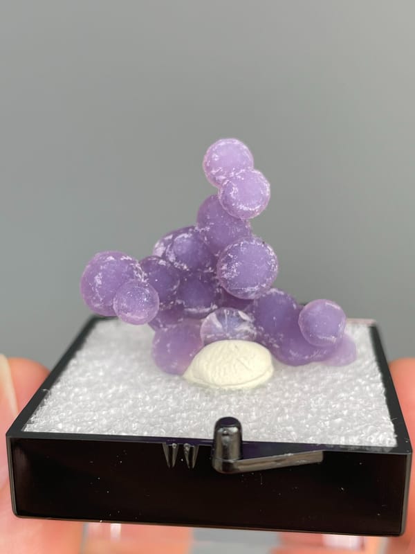Cluster of purple botryoidal grape agate spheres from Indonesia, in a box, reverse side