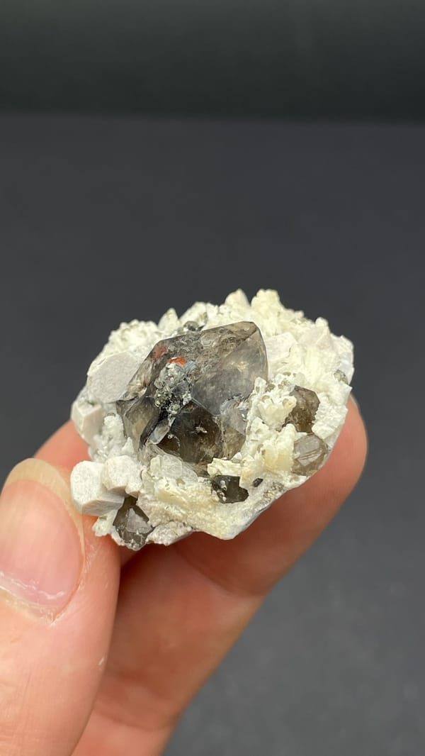 Smoky quartz crystal in cream feldspar from Yunxiao, Fujian, China, close-up of the crystal faces