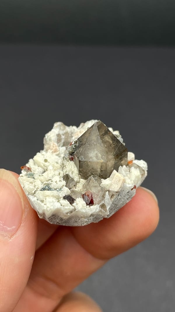 Smoky quartz and red garnets in white feldspar from Yunxiao, Fujian, China, close-up of the crystal faces