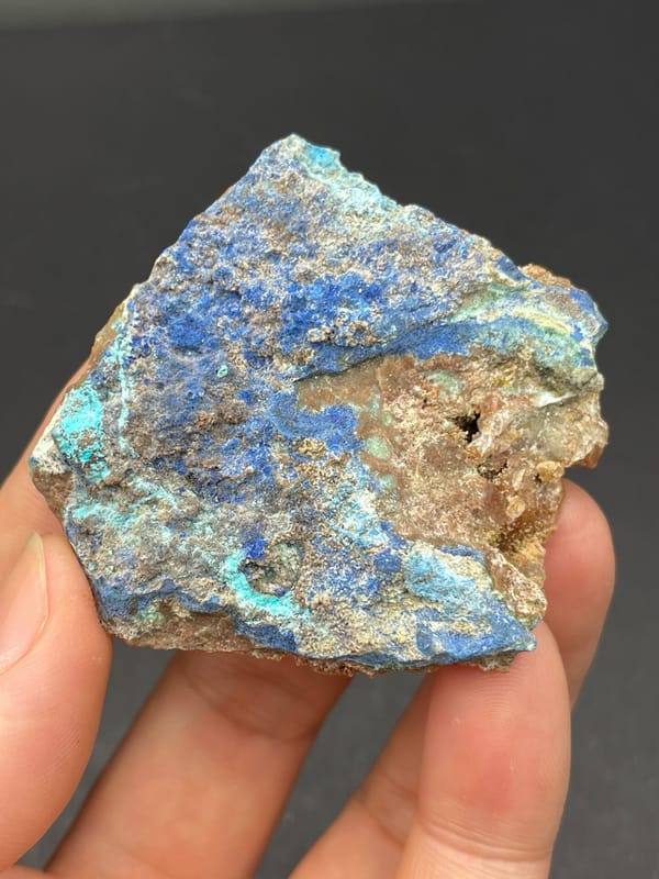 Deep blue azurite crust spread across a rock slab from Yunnan, China, held in hand