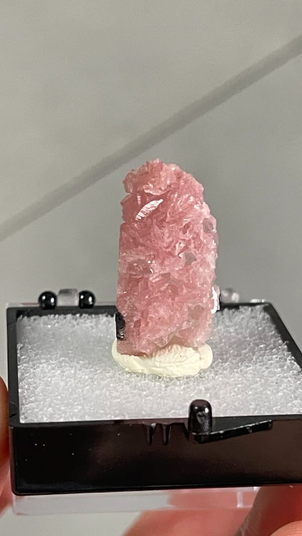 Rose-pink rhodochrosite crust from Wuzhou, Guangxi, China, in a display box, close-up of the crystal faces