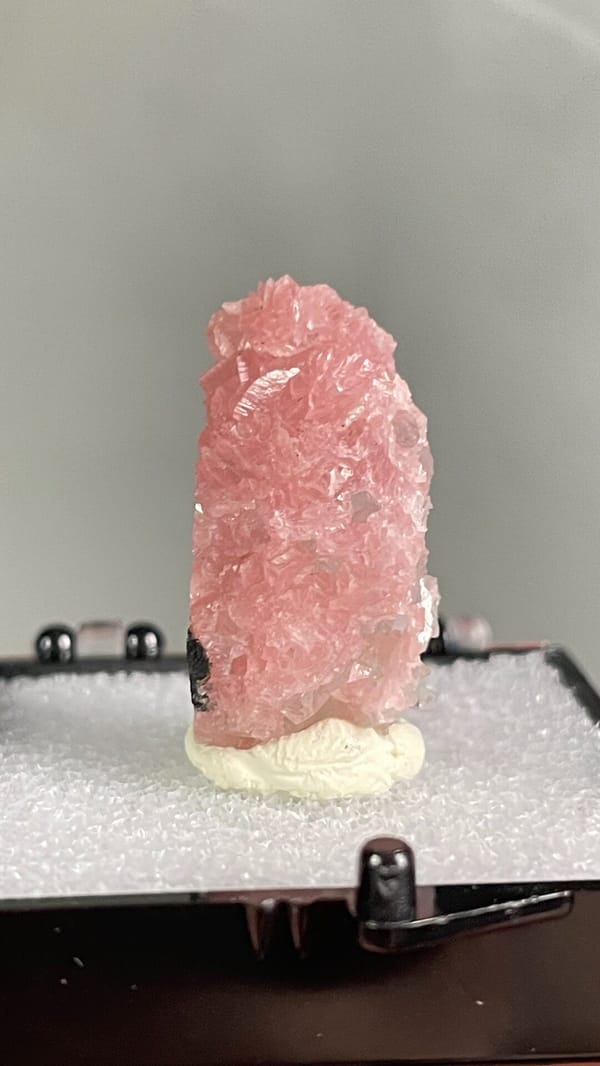 Rose-pink rhodochrosite crust from Wuzhou, Guangxi, China, in a display box, top view