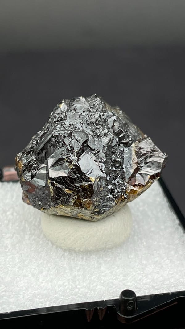 Dark brown Tennessee sphalerite crystal group from the USA, in a display box, detail of the matrix contact