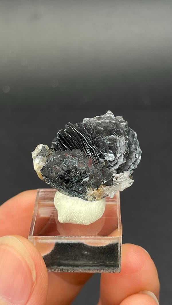 Dark metallic specular hematite flower from Jinlong, Guangdong, China, detail of the matrix contact
