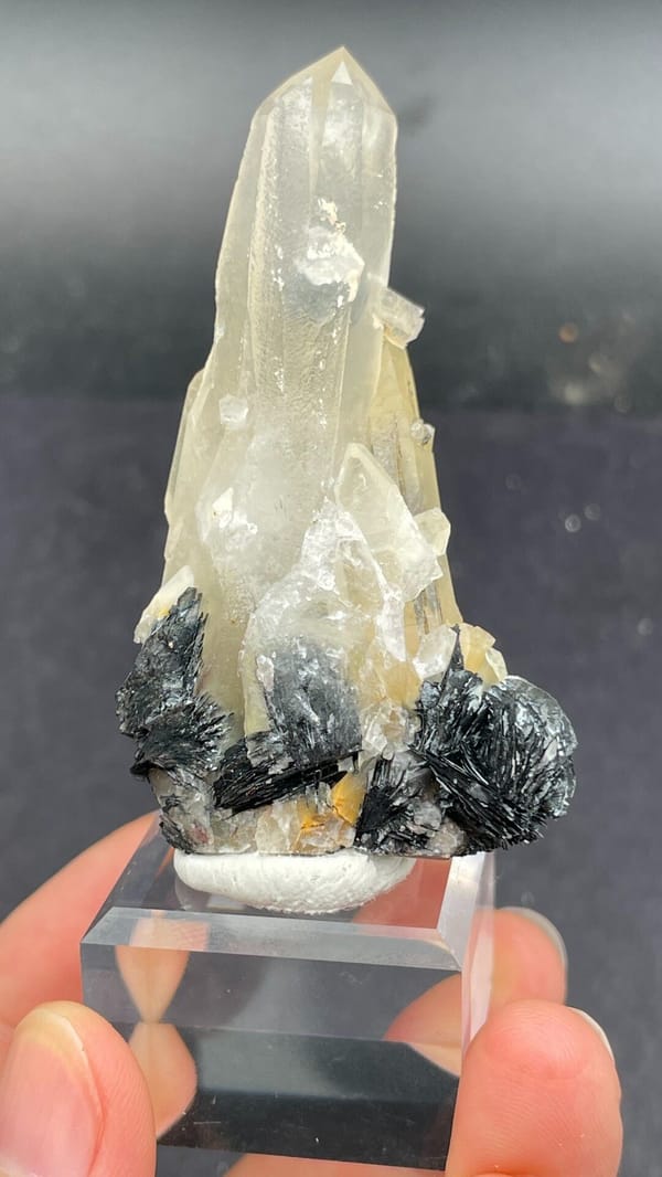 Pale quartz spire rising from black specular hematite, Guangdong, China, detail of the matrix contact