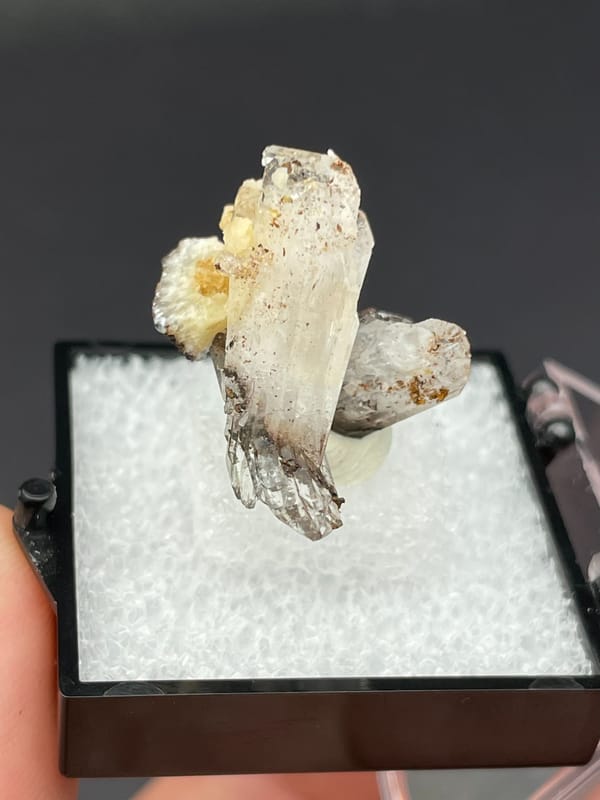 Colourless bladed creedite crystals with dark inclusions from Guizhou, China, close-up of the crystal faces
