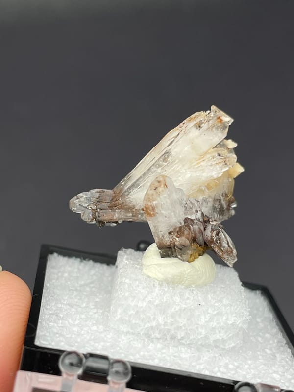 Colourless bladed creedite crystals with dark inclusions from Guizhou, China, reverse side